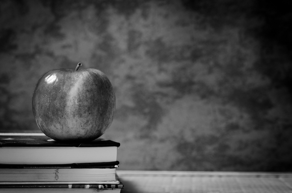 Generic B&W picture of an apple sitting on a stack of academic books.